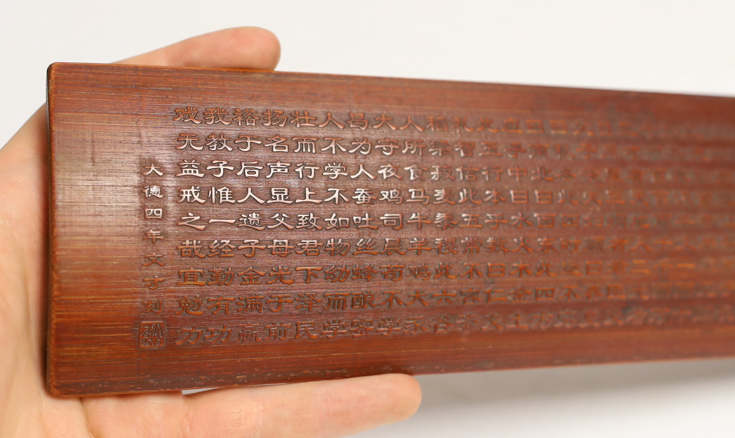 A Chinese bamboo inscribed wrist rest, carved in relief with columns of calligraphy, 30cm wide